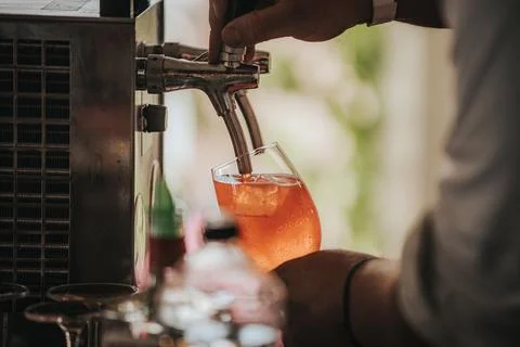 Bartender pouring a refreshing orange cocktail into a glass filled with ice.. Stock Photos