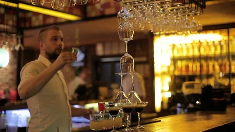 Bartender pouring shot of drink over glasses in flames Stock Footage