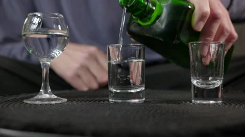 Bartender pouring strong alcoholic drink into shot glasses Stock Footage 334815255