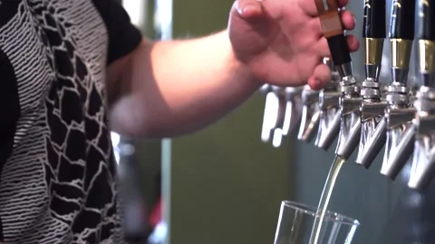 Bartender pouring from tap fresh beer into the glass in pub, Vidéo 145393574