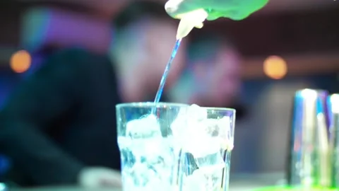 Bartender pouring transparent alcoholic drink  from a bottle into shot glasses Video stock 132948933