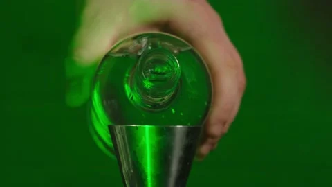 A bartender pours alcohol from a bottle into a measuring cup for a jigger Видео 185021516