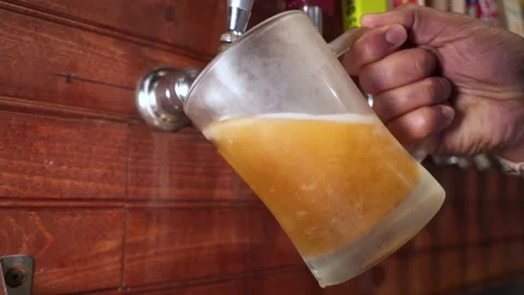 Bartender pours beer from tap, hand pulls draft into frosted mug, slow Stock Footage 144230522