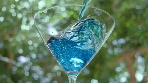 Bartender Pours a Bright Blue Cocktail into a Martini Glass Stock Footage 76205432