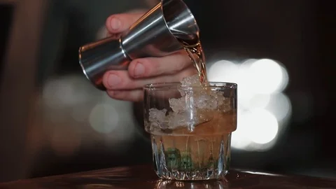 Bartender pours cocktail from measuring cup into ice with mint Vídeo Stock 128072041