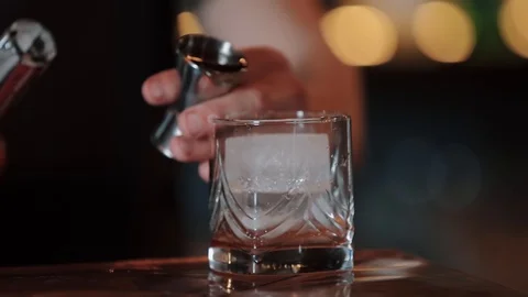 Bartender pours cocktail from measuring cup into glass.Old fashion. close up Video stock 128295530