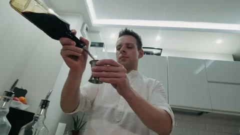 Bartender pours coffee liqueur into jigger and places glass bottle on bar Stock Footage 134035568