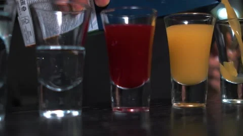 Bartender pours colorful drinks into small glasses close-up Stock Footage 141281065