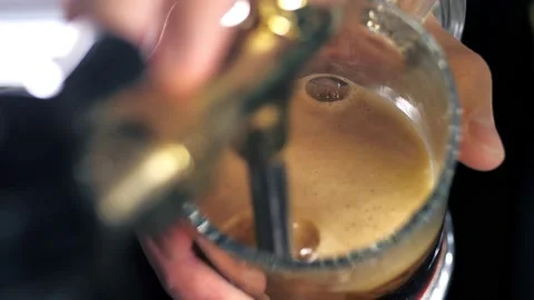 The bartender pours dark beer into a beer glass behind the counter.The bartender Stock Footage 169888216