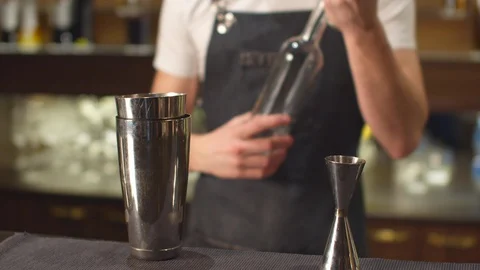 Bartender pours different alcohol in shot glass and shaker Stock Footage 123681136