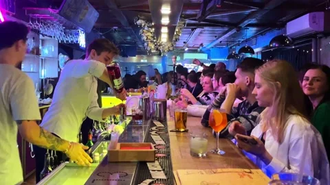 Bartender pours drinks to a crowd of men and women having fun. russia Stock Footage 213558743