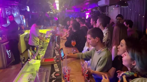 Bartender pours drinks to a crowd of men and women having fun. russia Stock Footage 253997438