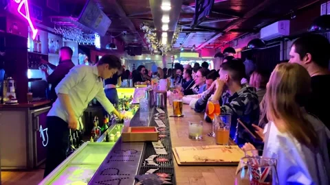 Bartender pours drinks to a crowd of men and women having fun. russia Stock Footage 253997447