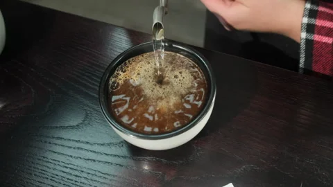 Bartender pours hot liquid from kettle preparing drink Stock Footage 306625595