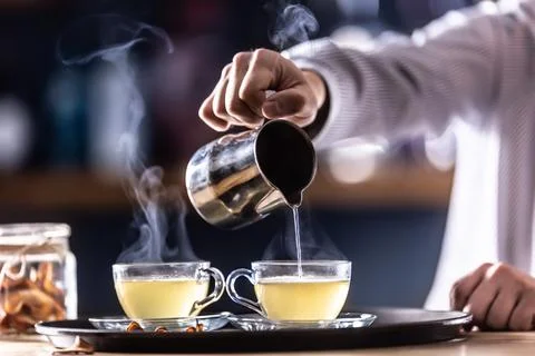 The bartender pours hot mulled wine or a winter whiskey drink Hot Toddy Фото