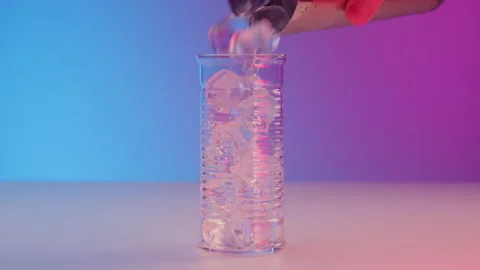 Bartender pours ice cubes from shaker into a beautiful narrow fluted glass on a Stock Footage 239422931