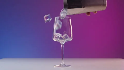Bartender pours ice cubes from shaker into a beautiful cocktail glass on a Stock Footage 246386030