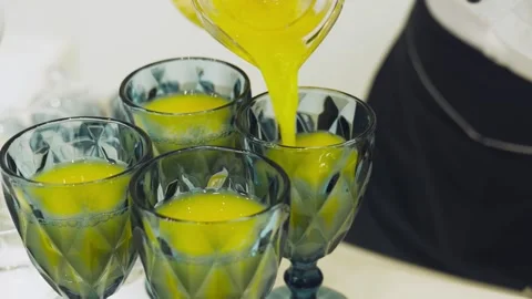 Bartender pours orange juice into elegant glasses at buffet or restauran Stock Footage 314254302