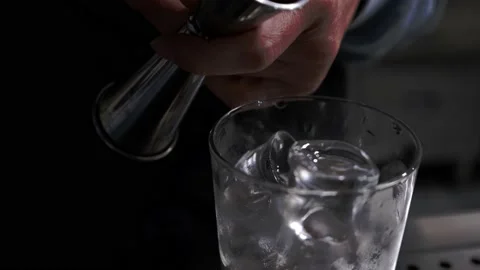 Bartender pours syrup into the glass with thin stream on ice cubes. Close-up Stock-Footage 130889195