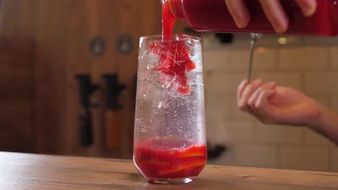 The bartender pours thick berry syrup into a glass to make berry lemonade. Stock Footage 345131991