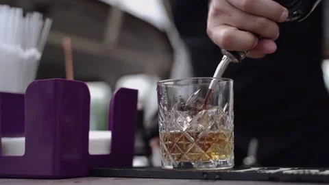 The bartender pours a thin stream of alcohol into a glass Stock Footage 138771193