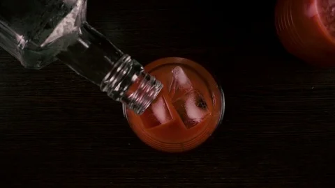 Bartender pours vodka from a bottle into a glass with juice top view. Slow Stock Footage 76490368