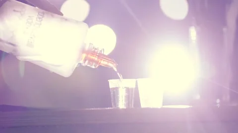 A bartender pours vodka into two glasses at a night party Stock Footage 221922995