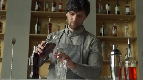 Bartender pours whiskey and cola into an iced glass at the bar. Preparing Stock-Footage 153458467