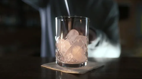 Bartender pours whiskey to the jigger and then to the glass with ice Stock Footage 143589497