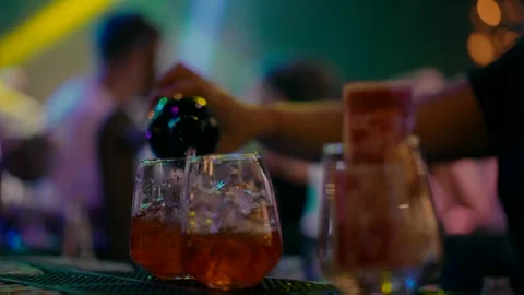 A bartender pours whiskey into two glasses at a night party. Video stock 244258401