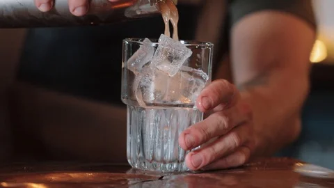 The bartender pours white coctail Tequila Sunrise into a glass with ice. Close Stock Footage 129111099