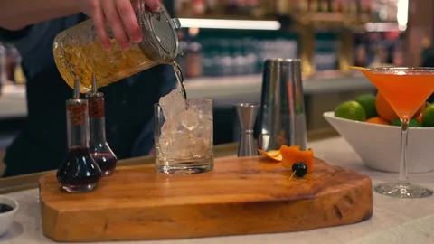 Bartender prepares elegant old fashioned cocktail at a classy modern hotel bar Stock Footage 280494798