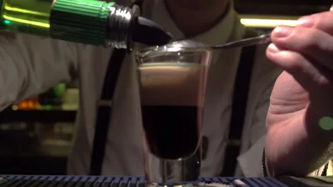Bartender prepares a layered shot at a bustling bar during a lively night out in Stock Footage 291953943