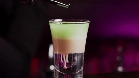 The bartender prepares a multi-layer cocktail in a glass, dripping liquor 스톡 동영상 159140066