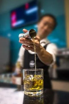The bartender prepares a portion of whiskey with ice on the bar Stock Photos