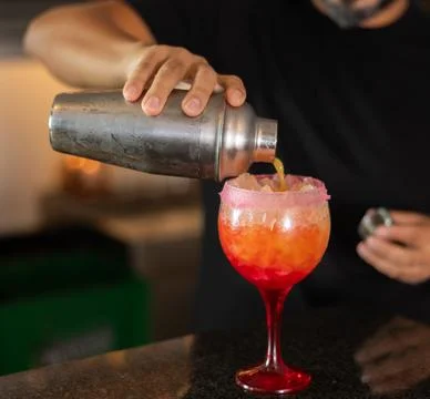 Bartender prepares preparing refreshing tequila sunrise drink - cocktail tequila Фото