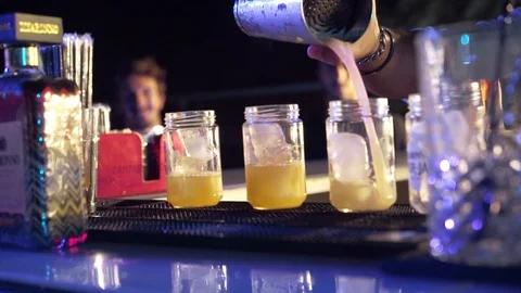 Bartender Preparing and Serving Cocktails with a night ambience Stock Footage