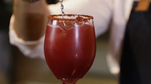 Bartender preparing a cocktail on a bar counter. Mixing with a metal mixer wi Stock Footage 147680283