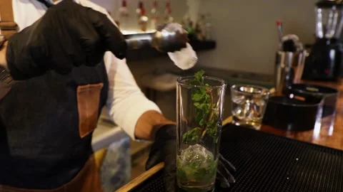 Bartender preparing a cocktail on a bar counter. Making ice with a metal tong Stock Footage 147680308