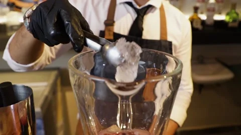 Bartender preparing a cocktail on a bar counter. Making ice with a metal tong Stock Footage 147680316