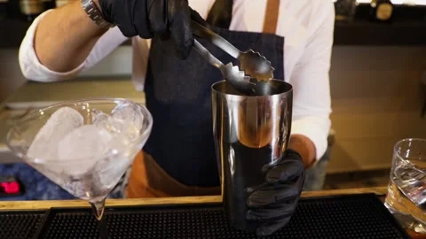 Bartender preparing a cocktail on a bar counter. Making ice with a metal tong Stock Footage 147680346