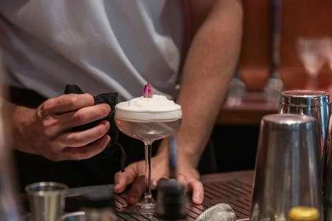 Bartender preparing cocktail with foam and decorative flower garnish Stock Photos