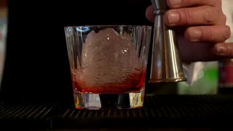 A bartender preparing a cocktail in a glass with ice at the bar. Stock Footage 244941080