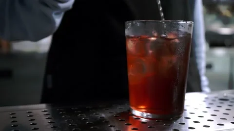 Bartender is preparing cocktail, stirs ingredients bar spoon in glass, close-up Stock-Footage 130889193