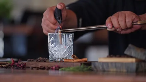 Bartender preparing a craft cocktail smoking cinnamon whiskey glass torch Stock Footage 288038684