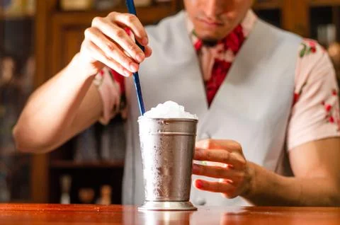 Bartender preparing delicious mint julep cocktail at table. Stock Photos
