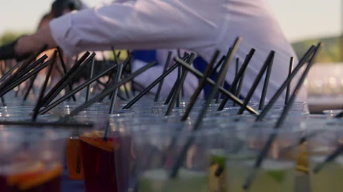 Bartender preparing rows of colorful drinks with straws at outdoor event Video stock 342768363
