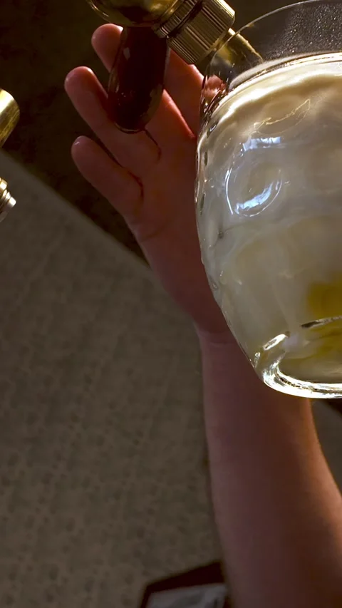 Bartender pulls frothy Czech lager beer into glass from brass taps Stock Footage 328389681