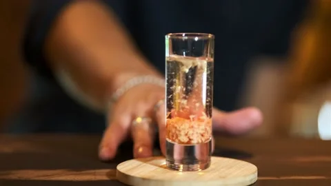 The bartender pushes forward a glass with a ready drink: baileys in sambuca. Stock Footage 148246248