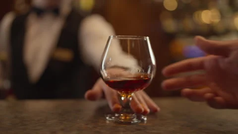 Bartender pushes a glass of brandy towards the guest. Close-up of a bar counter Stock Footage 273034167